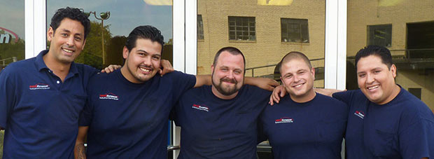 Three men in blue shirts are posing for a picture.
