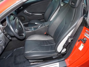 A red car with black leather seats and steering wheel.