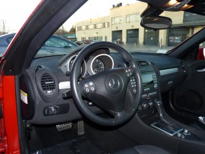 A car is shown with the dashboard and steering wheel.