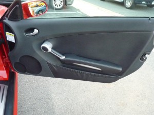 A car door handle with the steering wheel in view.