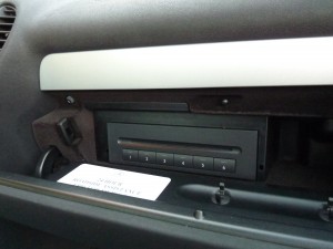 A car radio with the door open and some papers on it.