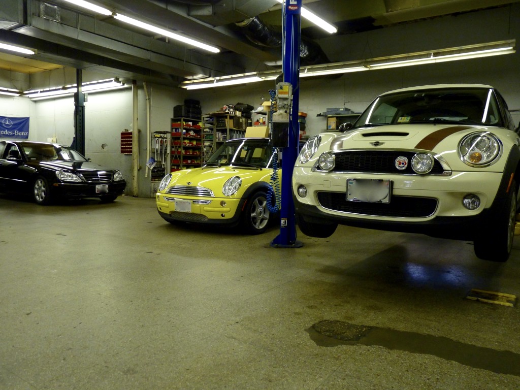 A garage with two cars parked on the floor.