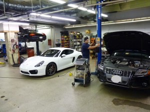 A man working on two cars in a garage.